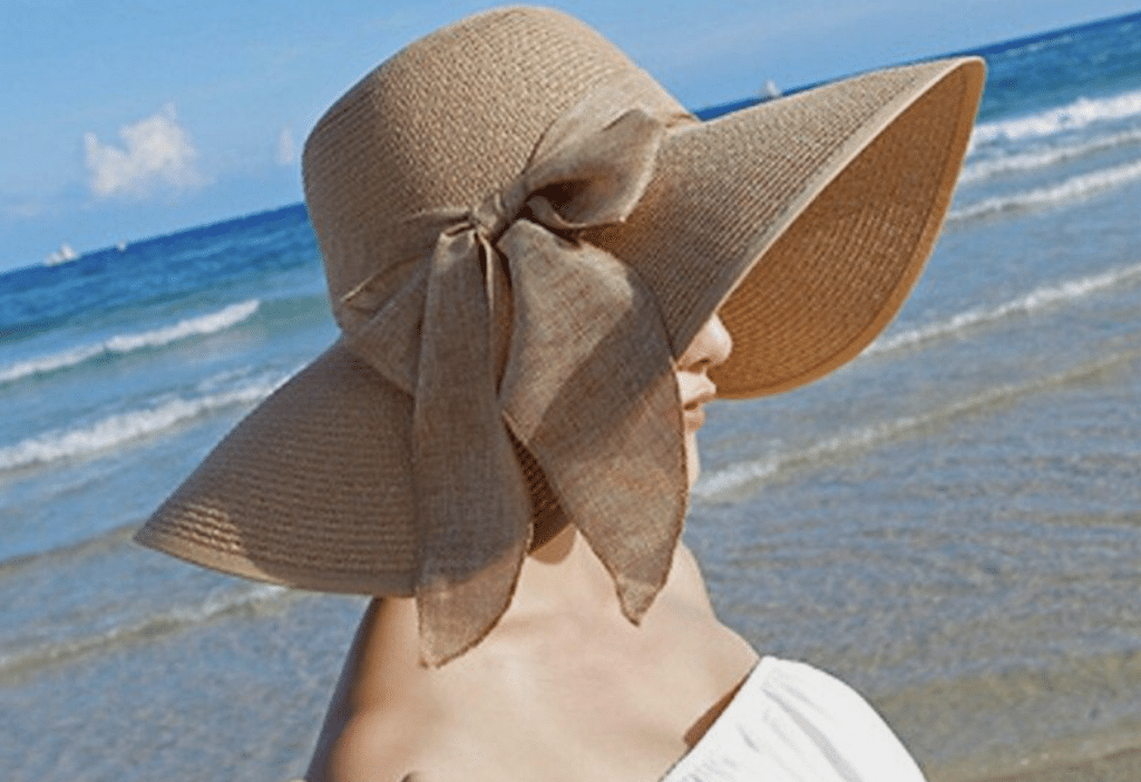 a casual change in style - woman by the beach in strapless dress and floppy straw hat