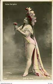 vaudeville emerges - scandalous woman on stage with very short costume and head dress holding flowers