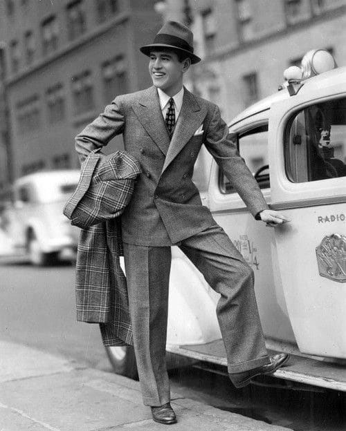 gentlemen of the golden age - man in 1940's suit with coat standing by a taxi