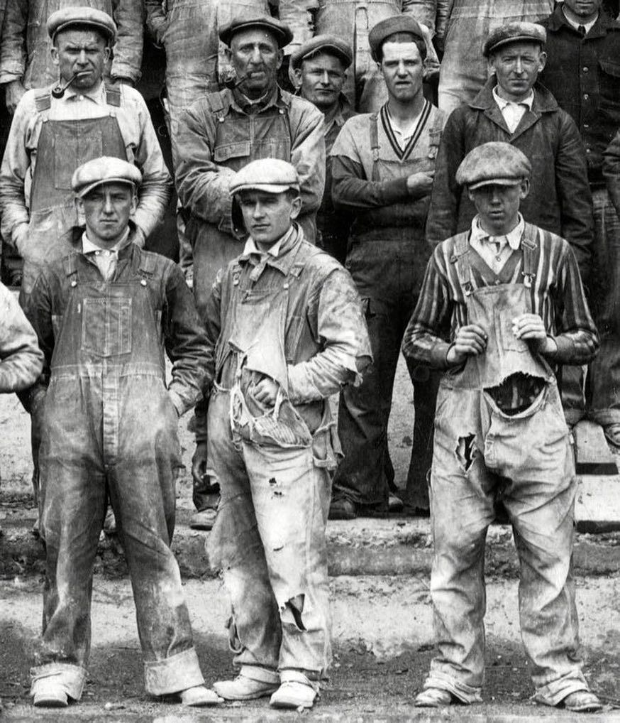 the edwardian gentleman - group of men in working overalls and newsboy caps
