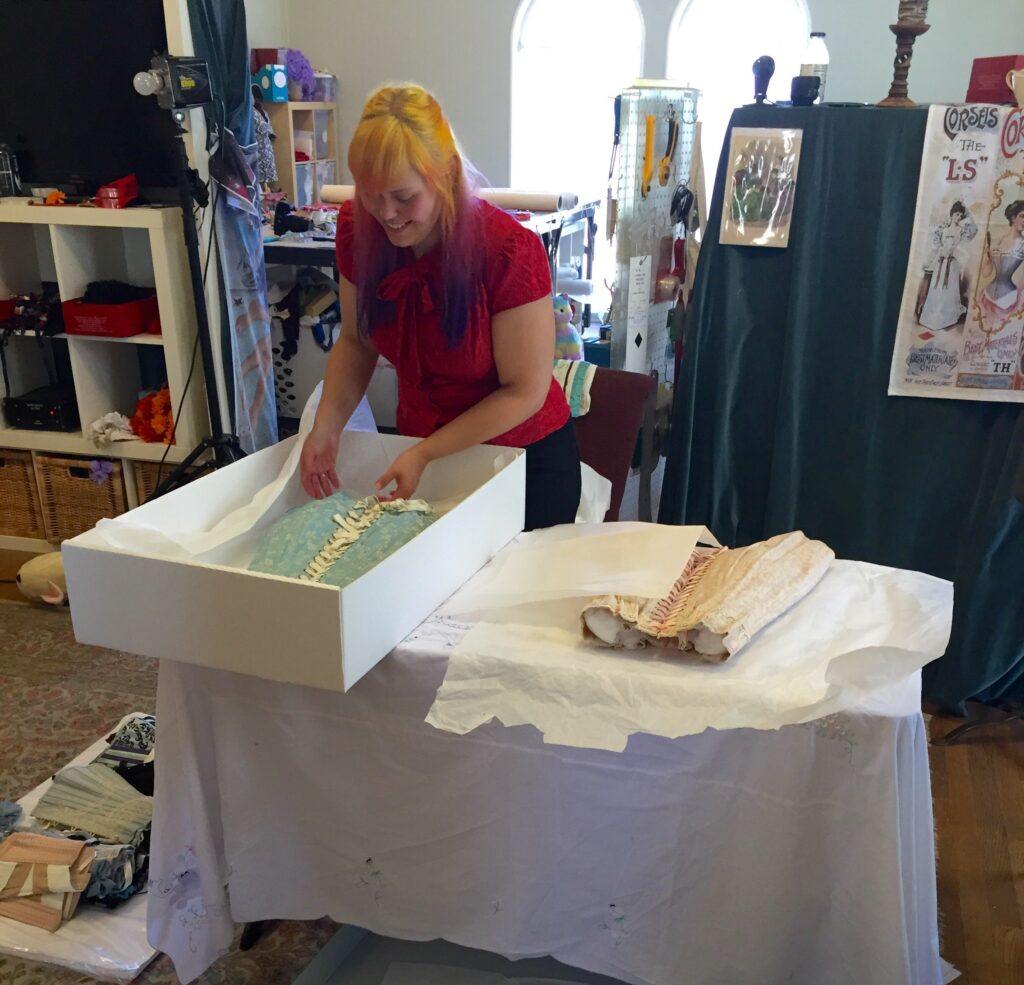 maintenance and care for vintage corsets - a textile conservator at a corsetry museum packing away vintage corsets