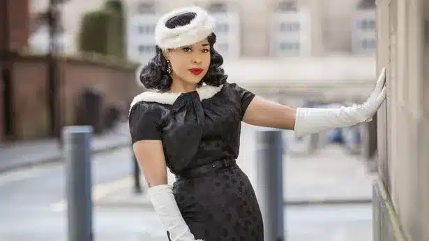 1940's lady wearing 3/4 white gloves with matching accessories contrasted against her black spotty dress