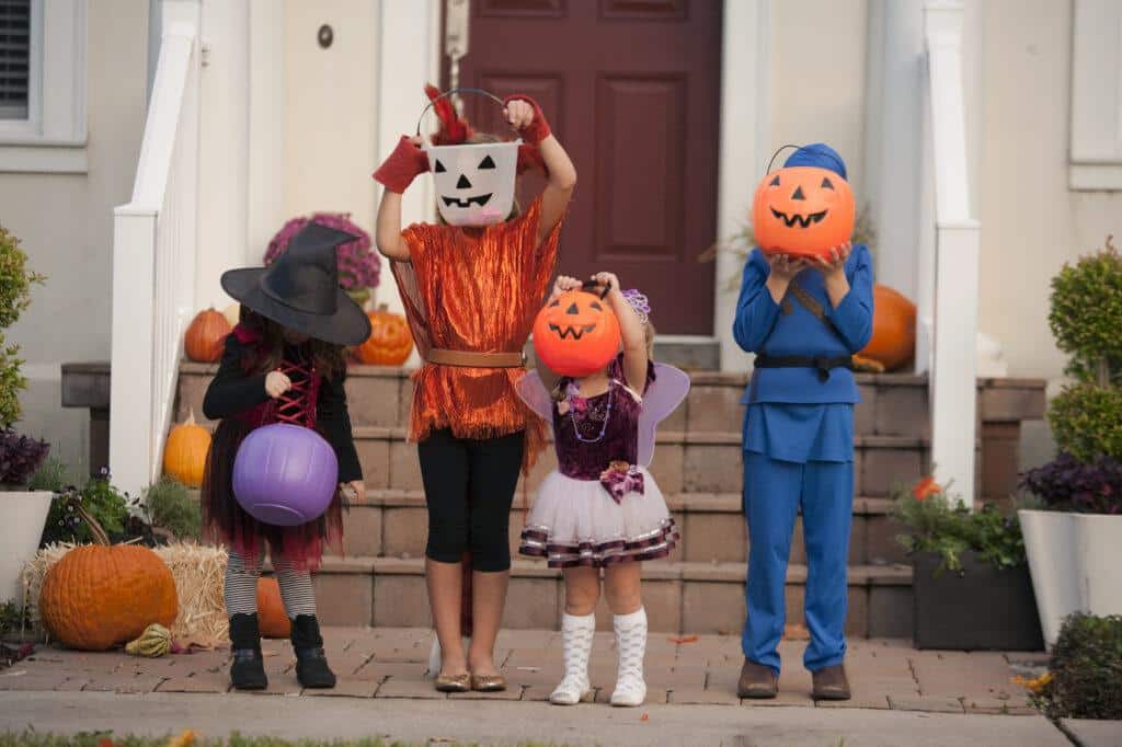 the dark elements of halloween - modern day children dressed in costumes with pumpkin or witch costumes