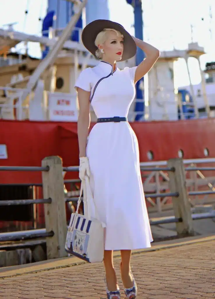 when the swing style really took off - woman at the docks dressed in fitted white dress and large sunhat