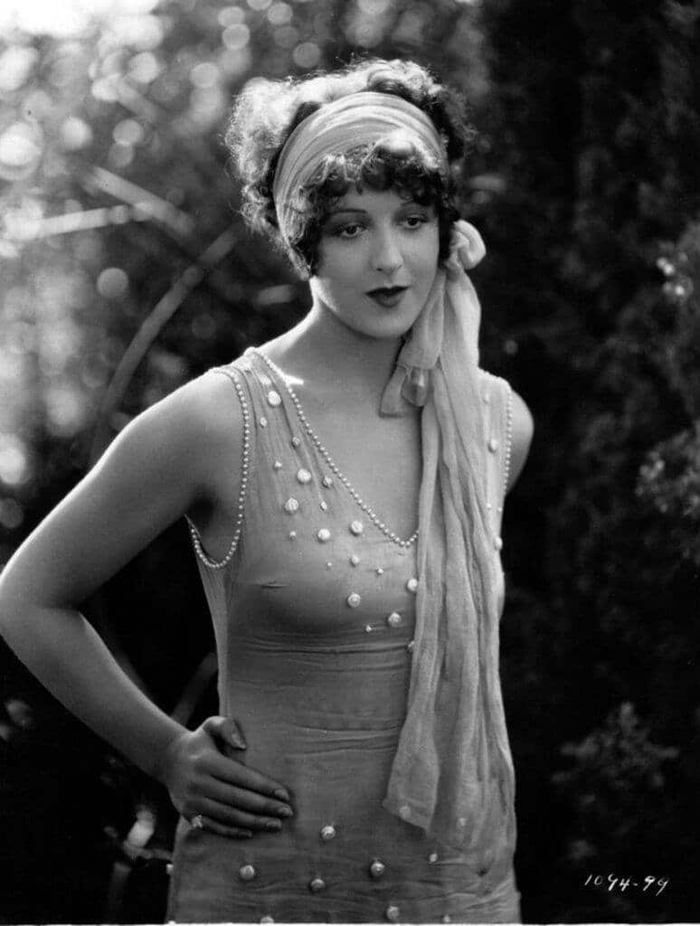 1920's flapper laldy with head scalf and sleeveless fitted evening gown in pearl trims