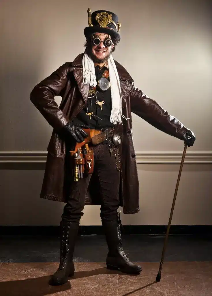 steampunk aesthetic - DIY man with steampunk coat top hat and walking stick holding trade tools in a belt around his waist