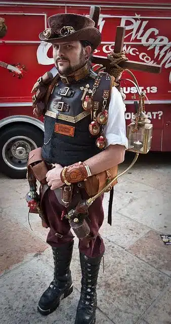 reviewing men's steampunk fashion - man wearing DIY steampunk attire with elements of hunting in vest including cogs and self attached candle torch