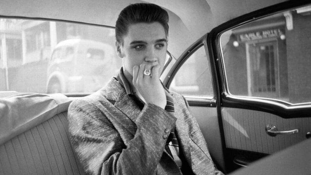 the lasting legacy of vintage icons in contemporary fashion - elvis presley sitting in the back of 1950's car smoking a cigarette