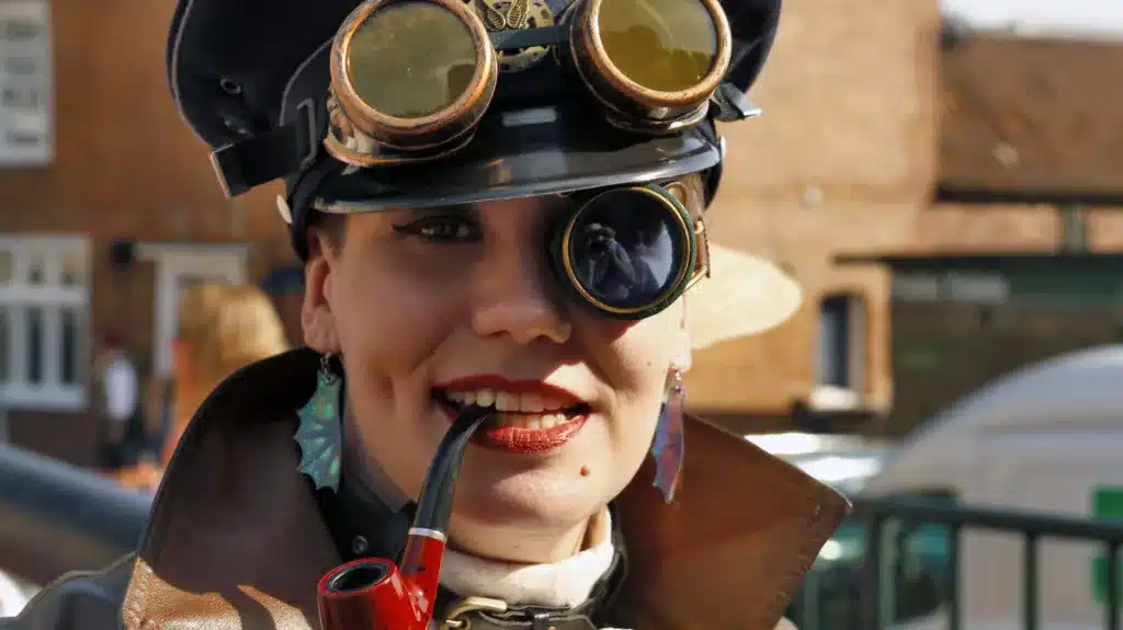 the steampunk feminine woman, lady wearing aviator steampunk hat and google on one eye sporting a smoking pipe