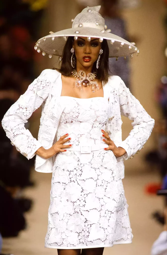 why vintage icons captivated the world - tyra banks in a 60's revival shift dress and jacket wearing a lampshade hat on the runway