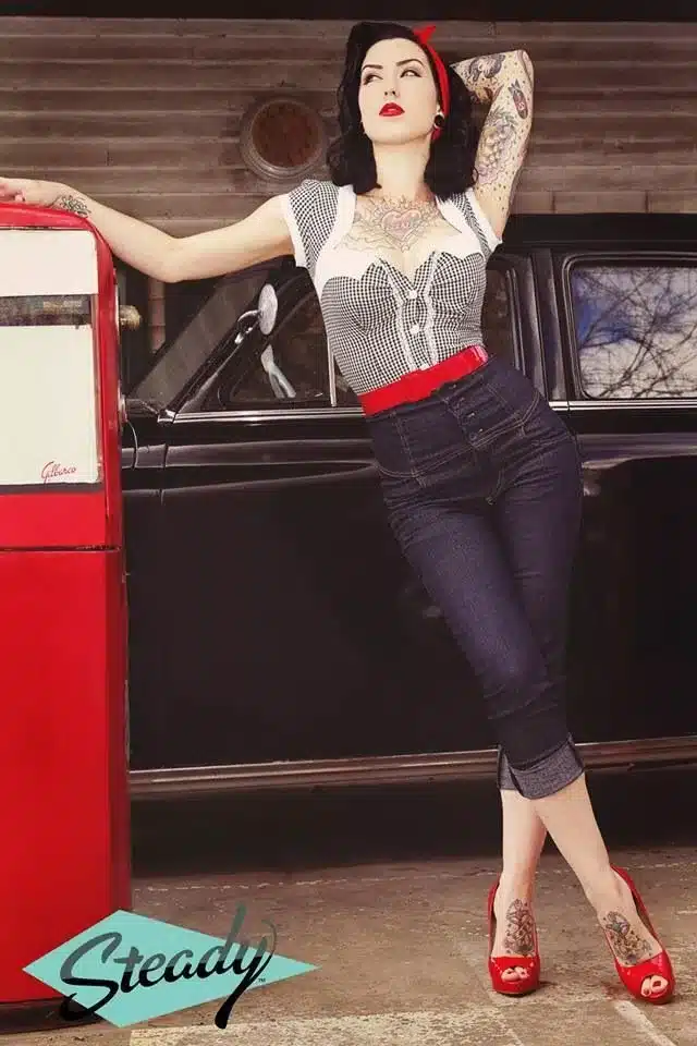 key elements of rockabilly fashion, confidence and rebellion - woman sporting tattoos on arms and feet wearing blue denim and 50's retro top with accessories