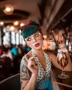 defining the rockabilly rebel - woman sitting a a bar with blue hair, tattoos and polka dot dress and accessories