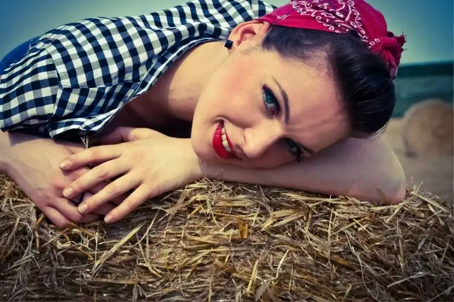 defining the rockabilly rebel - woman in checked shirt and headband laying on straw