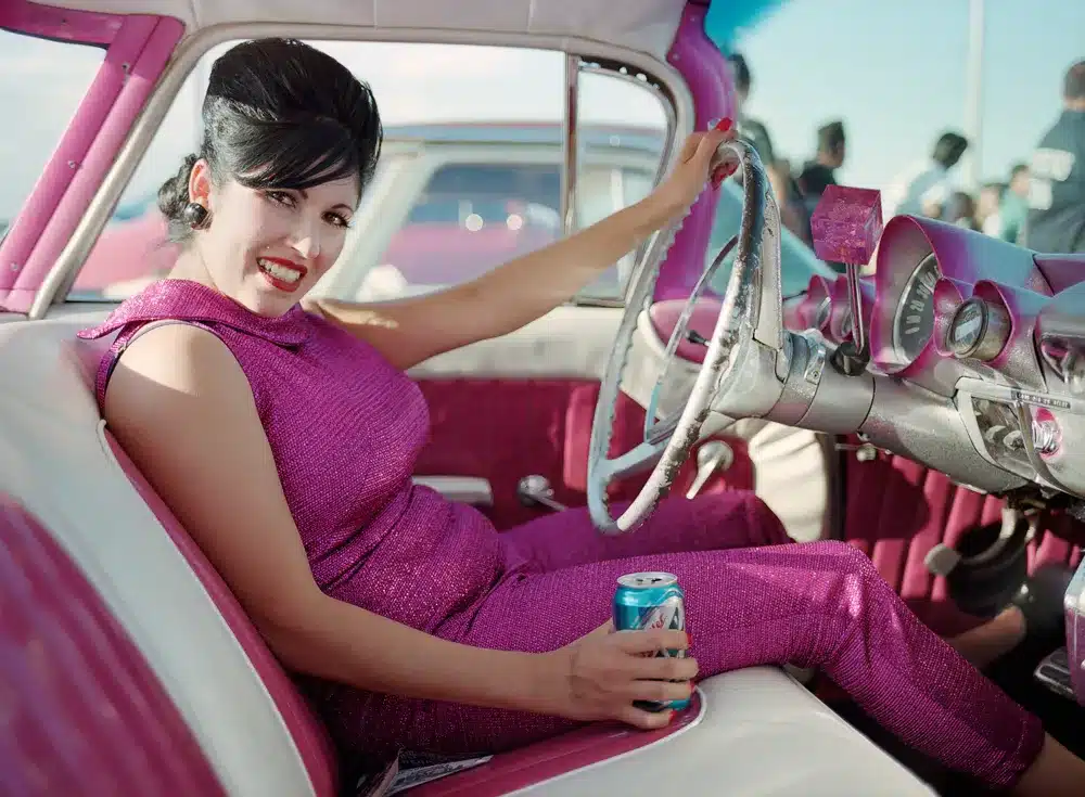 the enduring charisma of rockabilly fashion and it's place in contemporary style - woman in 50's vintage car complimenting the colours with her lame pants suit