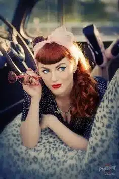 key elements of rockabilly fashion, bold lips and cat-eye liner - woman inside car sporting bright lipstick and eye makeup with bangs hair