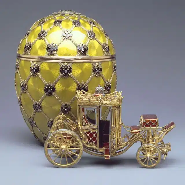 the symbolic grandeur of faberge eggs - the imperial coronation egg circa 1897 in yellow gold with gold and red carriage beside it