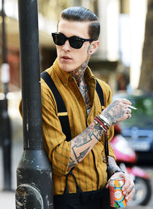 key elements of  rockabilly fashion, greaser look - man embracing the greaser style with slick hair, shades, braces and tattoos