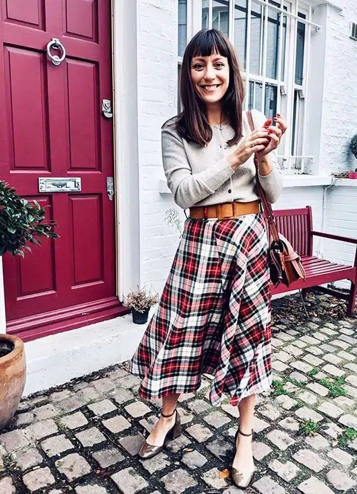 vintage workwear essentials - from practicality to empowerment, woman in red/white tartan skirt and beige cardigan