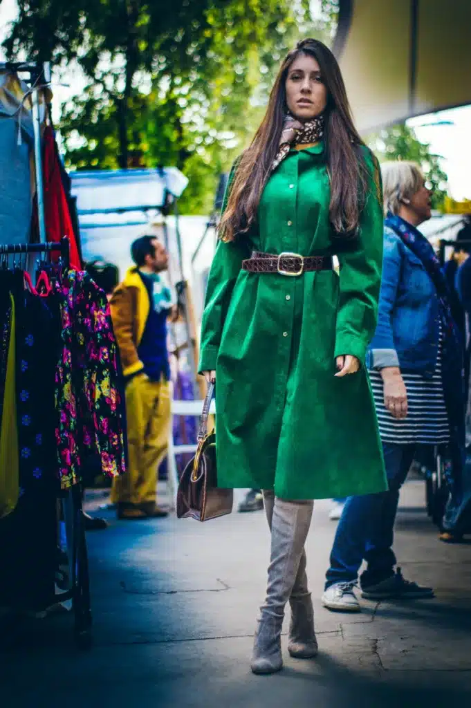 mixing and matching vintage with modern-woman dressed in green coat belted at the waist and light coloured boots