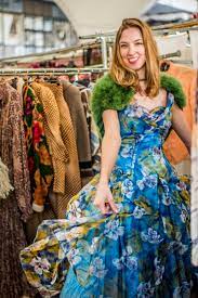 mixing and matching vintage with modern-woman at a thrift shop trying on blue floral chiffon dress and green shrug