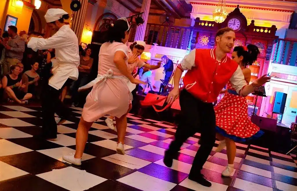 the importance of costume wearing to a themed party - group of people dancing at a diner in 50's costume