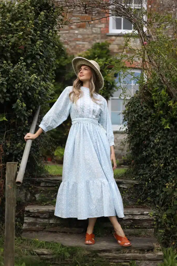 Key vintage trends making a comeback - woman wearing a long sleeved white maxi dress with fitted belt and lace