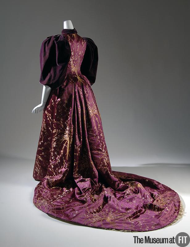 Model wearing a 1894 magenta floral brocade and plum velvet dress with silk satin and a train behind
