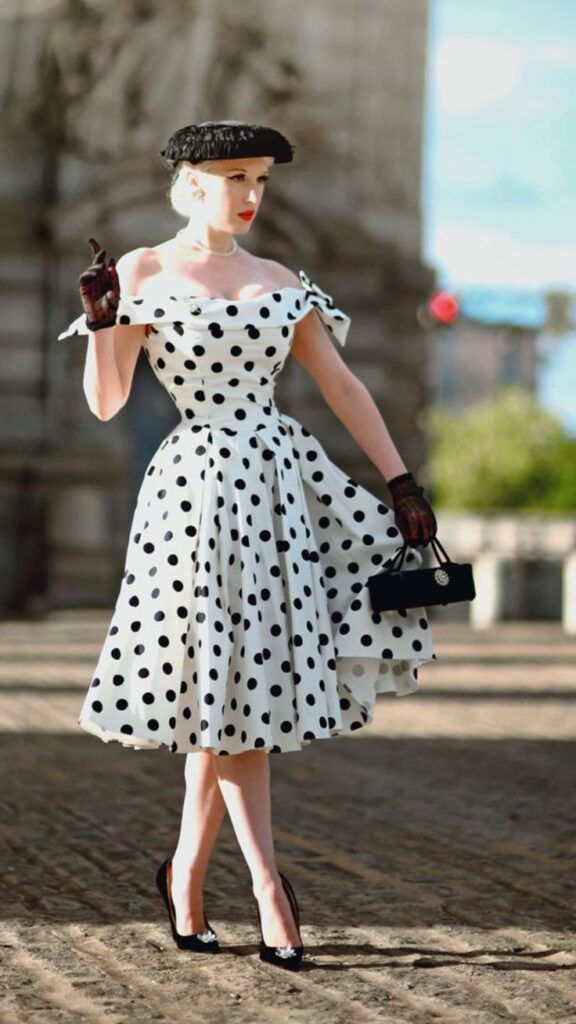 blonde lady in white polka dot dress with black accessories and hat