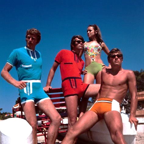 Group of guys with a woman wearing tight beach attire around late 1960's