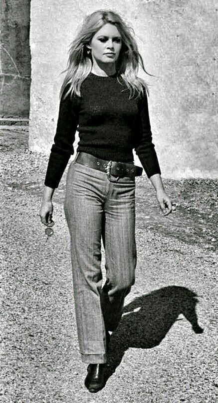 brigette bardot dressed in a dark sweater and hipster pants with a wide belt and boots