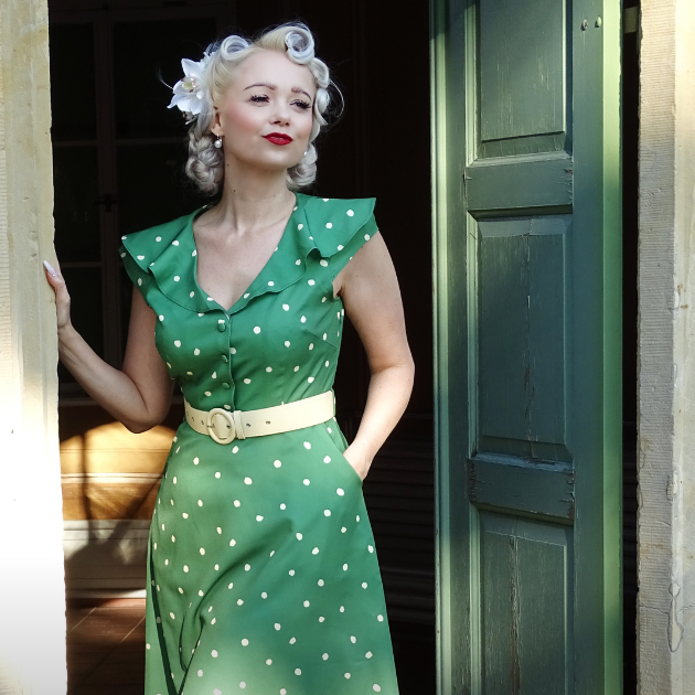 Blonde lady with finger rolled hair and a green summer spotted dress