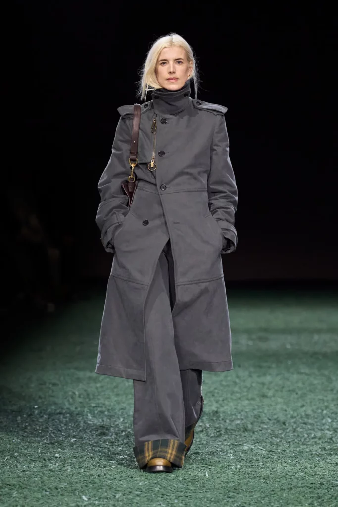 Model wearing Thomas Burbury trench coat with high neck and matching wide trousers trimmed in tartan