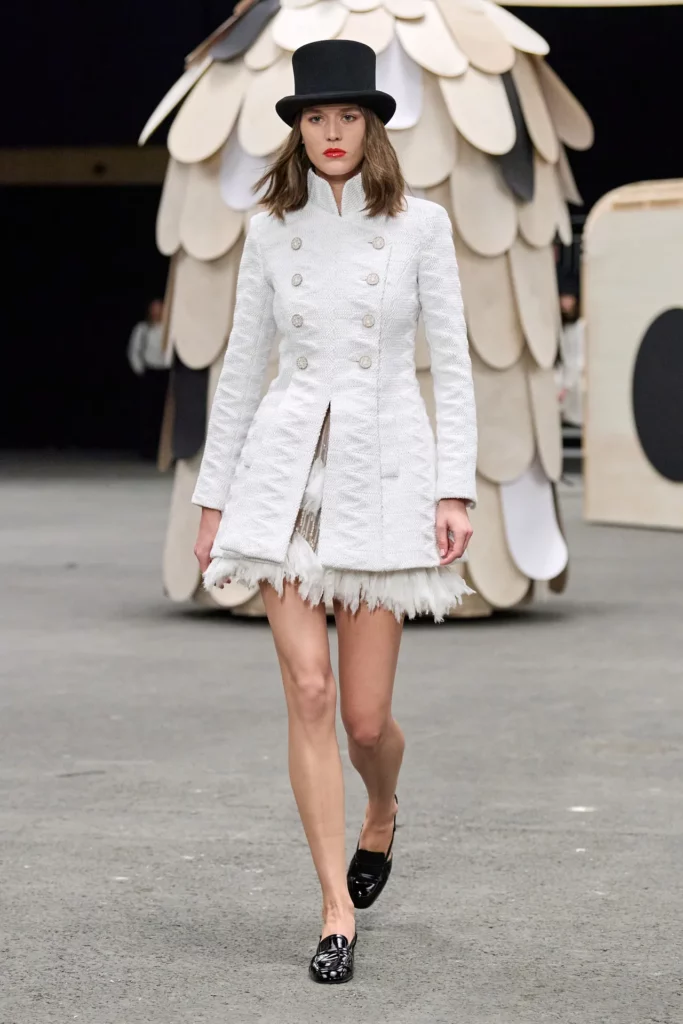 Model on catwalk dressed in Coco Chanel military inspired white jacket/coat