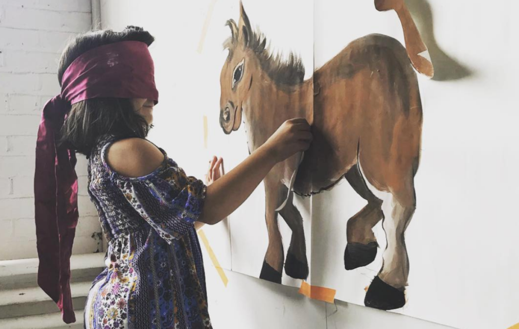 Girl with a scarf covering her face trying to pin the tail on a donkey poster