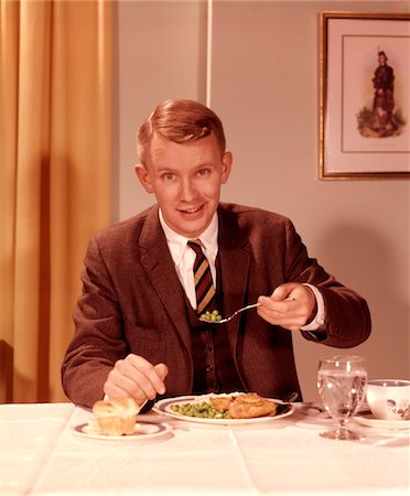 Man in a 3 piece suit sitting eating dinner at a set table