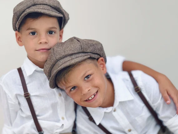 2 boys dressed in newsboy caps white shirts and suspenders