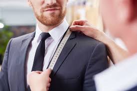 Tailor measuring a mans  suit lapel