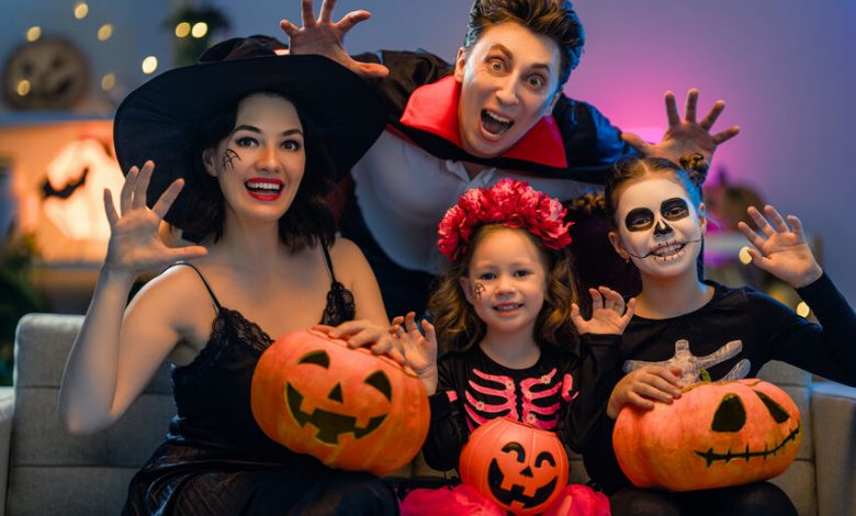 Family with 2 girls dressed up as gouls and witches holding pumpkins