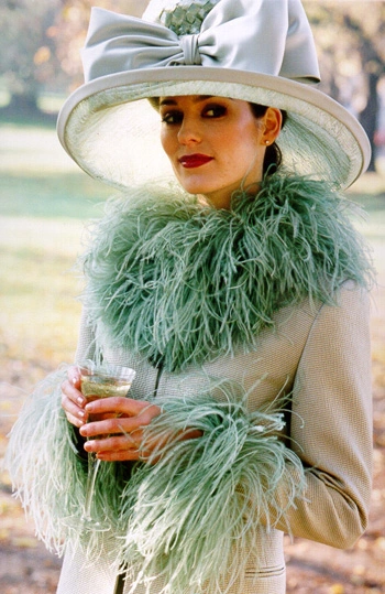 Lady in a wide brimmed bow hat with a light green suit adorned with ostrich feathers