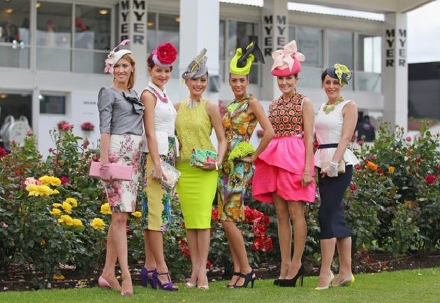 6 ladies posing for fashions on the field in bright coloured dresses and matching or contrast hats