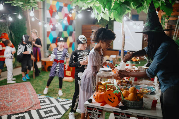 Children being served at a backyard halloween party with lots of lighting and food served