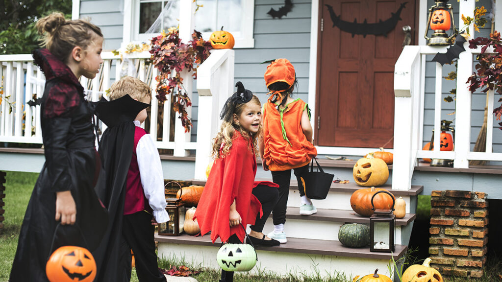 Children entering a home decorated with jack o lanterns and wearing costumes