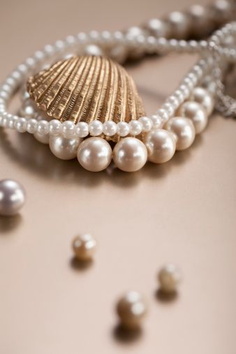 two strands of round pearls in wider and smaller size next to gold clam