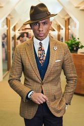 Man in tweed jacket with contrast waist coat and floral tie with trilby hat