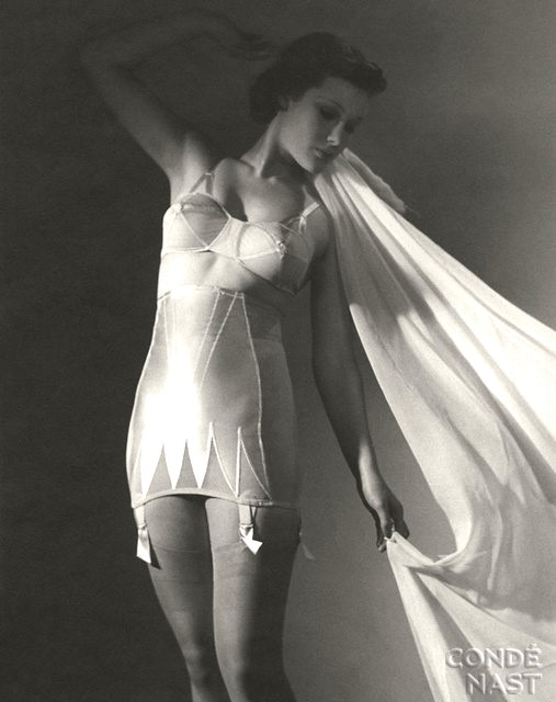 1940's lady in an all in one bra and corset girdle holding a light wrap