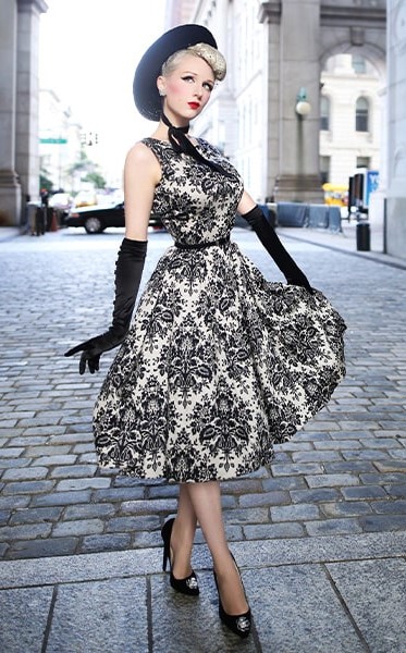 Lady in black and white tea dress with long gloves and a black hat