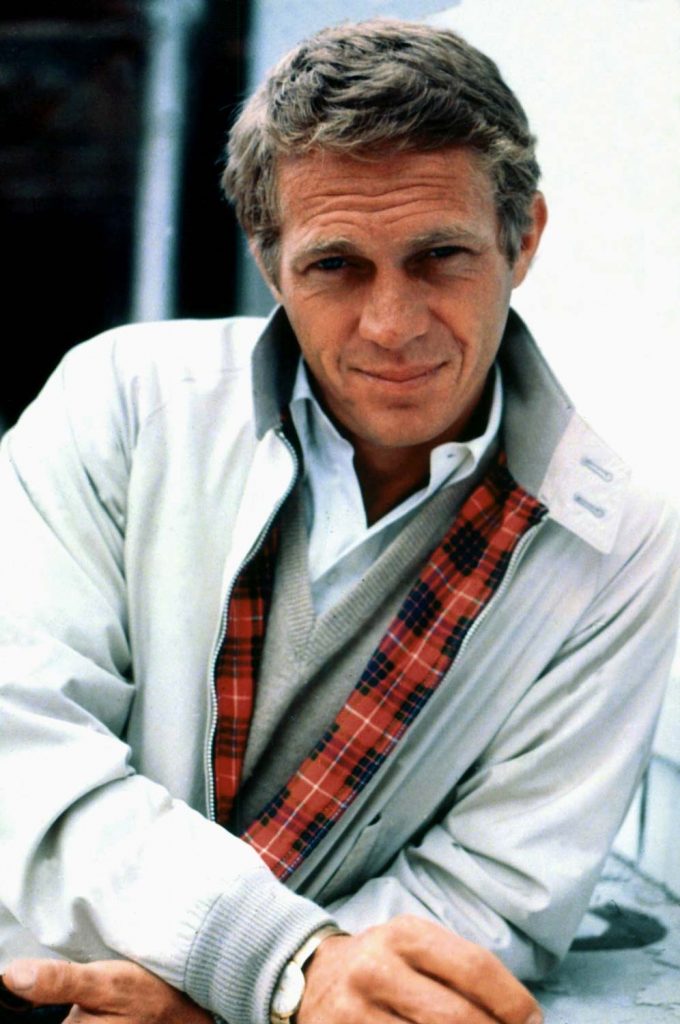 Steve McQueen in a casual zip jacket white shirt and beige jumper