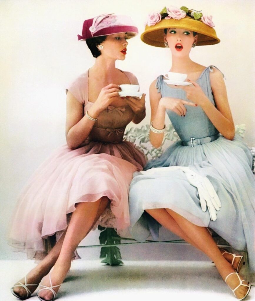 two ladies in adorned sun hats and fitted waist dresses in soft pastels with gloves