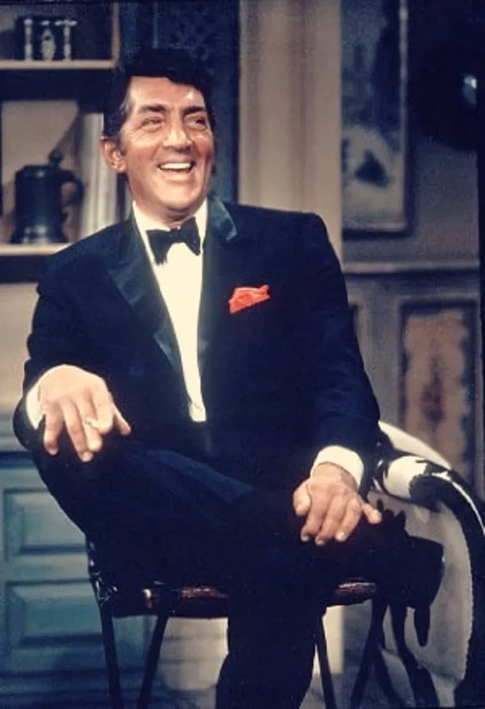 Dean Martin sitting on a chair wearing a black tuxedo