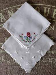 A set of 2 vintage cotton hankies 1 with coloured embroidery on it